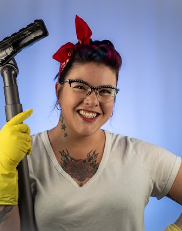 a woman with brown hair and a red bandana tied on her head holding a vacuum cleaner hose