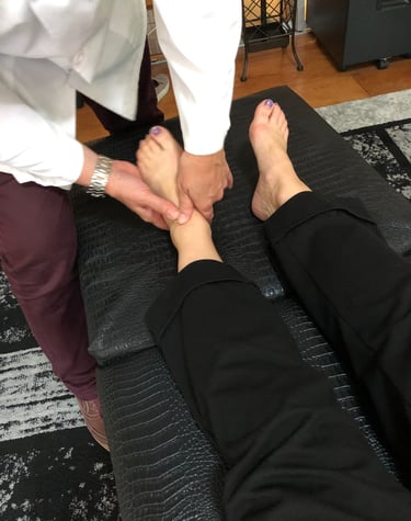 Dr. Lonna Denny performing a traditional adjustment to a patient.'s ankle