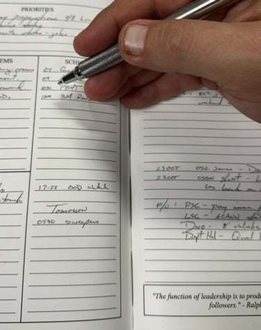 a person holding a pen and writing on a notebook