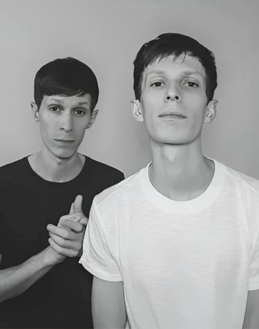 two men standing next to each other in front of a wall