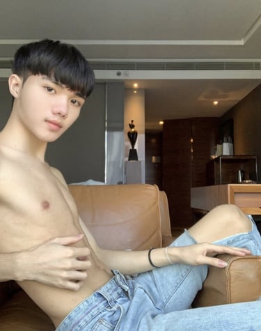 guy without a top wearing jeans sat on a sofa