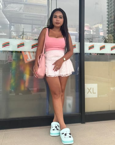 Lady therapist leaning against a shop window wearing short white skirt and sleeveless pink top