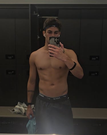 man taking a photo looking into a mirror wearing grey shorts