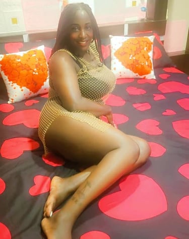 Lady wearing netted short dress and lying on a bed with red heart shaped bed sheet