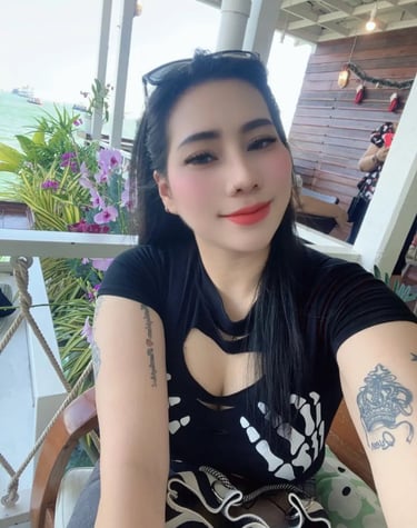 Lady wearing a black dress and tattoos showing on arms 