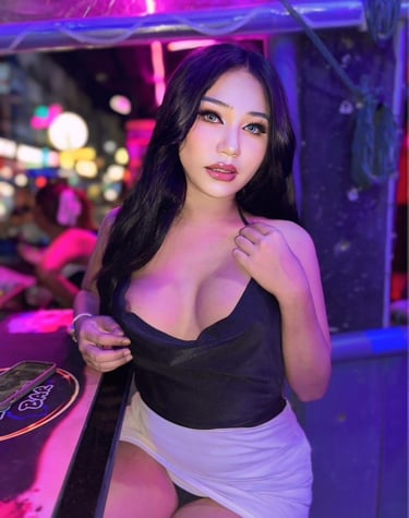 Beautiful Ladyboy with long hair wearing low cut black top and short white skirt