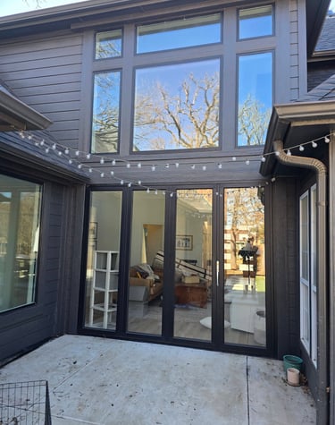 Modern dark grey home exterior featuring large black frame windows, freshly sealed and painted
