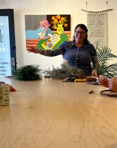 a woman is standing in front of a table with wreath making materials on it