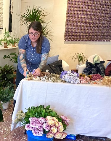 a woman is standing in front of a table with flowers