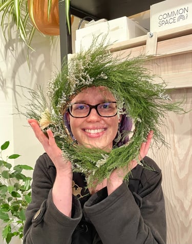 a woman holding a wreath of pine needles
