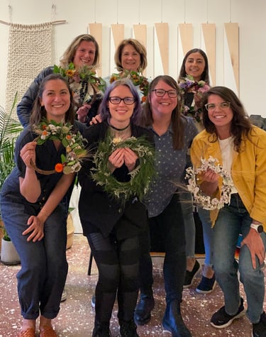 a group of women standing and showcasing wreaths
