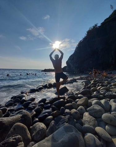 a man performing yoga on rocks in the sea