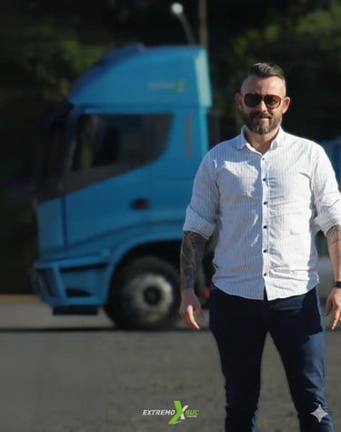 Representante da Extremo Sul Transportes posando ao lado de caminhão azul
