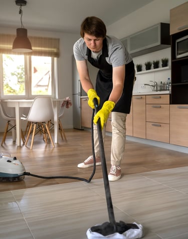 a man in a black apron and yellow gloves cleaning a floor