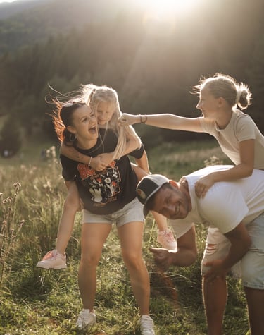 Smiling family in the field holding daughters on their back