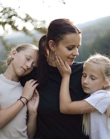 Mother holding her two daughters and smiling while her daughters are with closed eyes