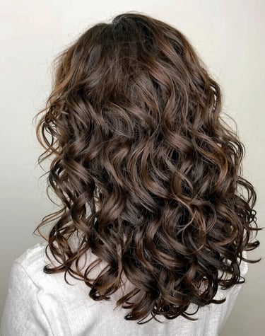 A joyful woman running fingers through her thick, lustrous hair in natural sunlight.