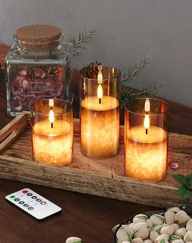 Three flameless LED glass pillar candles with remote control on a rustic wooden tray.