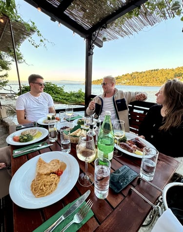 Guests smiling with food on plates at a seaside restaurant on Šolta during a private boat tour from Split