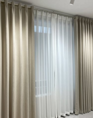 Sunlight filtering through soft, flowing cream curtains in a cozy living room.