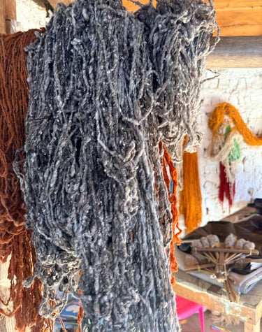 Fardos de hilo de lana cruda de color gris y naranja colgados en un taller de tejido textil tradicio