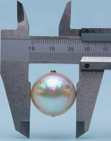 Close-up of a pearl being measured with professional calipers. The focus is on the precision of the shape, with a Soft Pearl Blue background.