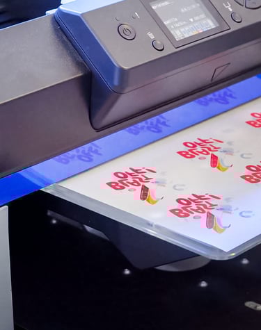 An Epson industrial inkjet printer creating custom colorful logo transfers on a clear film sheet.