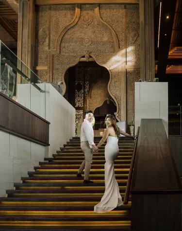 Couple walking down the grand staircase during a luxury prewedding photoshoot at Apurva Kempinski Bali