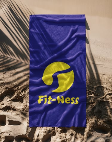 Blue Fit-Ness branded beach towel on sand under palm tree shadows.