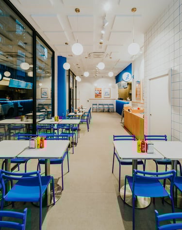 Interior de Flipa desde la entrada, con sillas azules, azulejos blancos y ambiente moderno