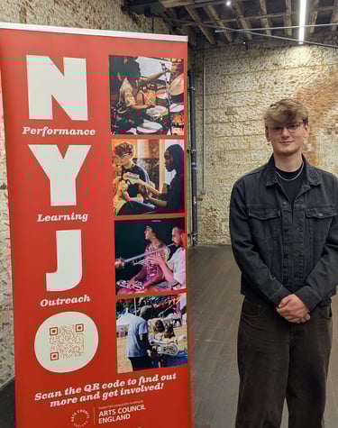 An image of Jamie Walker standing next to a NYJO sign