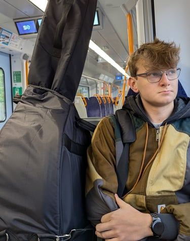 An image of Jamie Walker travelling on a train with his Double Bass