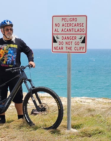 a man standing next to a sign at El Faro, Cabo Rojo