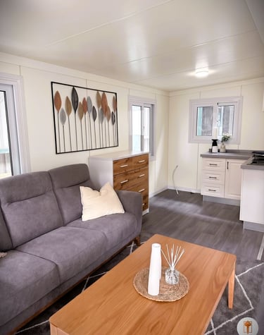 Modern tiny home living room with a grey sofa, wooden coffee table, and stylish wall art.