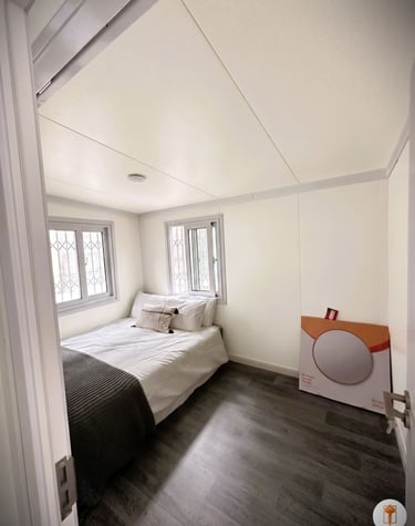 Modern small bedroom with a white bed, dark wood floors, and minimalist white walls.