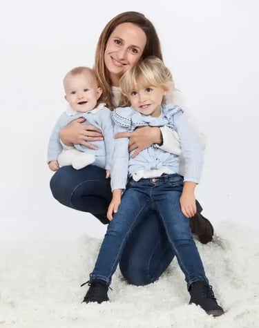 a woman sitting on a rug with two children