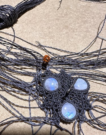 collier en cours d'élaboration, tissage très fin, coccinelle, fil gris Linhasita, peristerites, macramé , artisanat