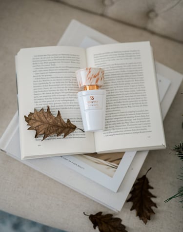 Un elegante flacone di profumo Olfazeta della linea Chogan poggia delicatamente su un libro aperto,