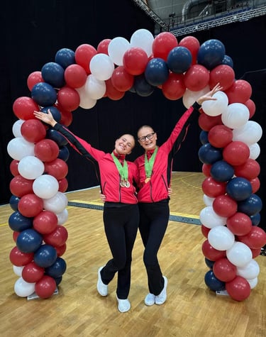 two women standing in front of a large arch shaped balloon