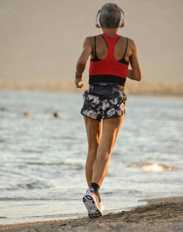 Woman running on the beach with a tennis racket