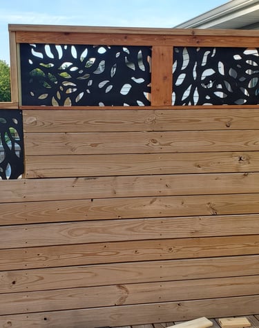 Custom wood privacy fence with decorative black laser-cut metal screens on a backyard deck.