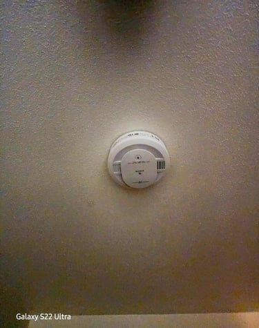 White Kidde smoke detector mounted on a textured ceiling for residential fire safety.