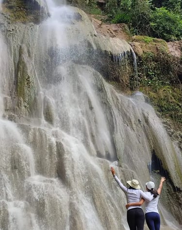 two people standing in front of a waterfall