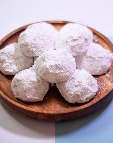 Plato de madera lleno de galletas redondas cubiertas de azúcar glass, conocidas como besos de nuez