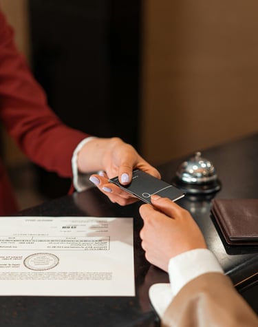 A hotel receptionist handing a black key card to a guest at the check-in desk.