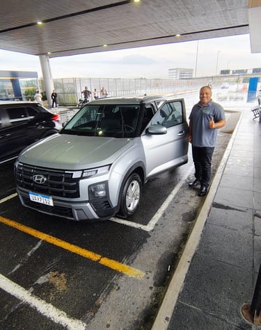 Motorista ao lado do carro posando para foto após finalizar mais uma viagem