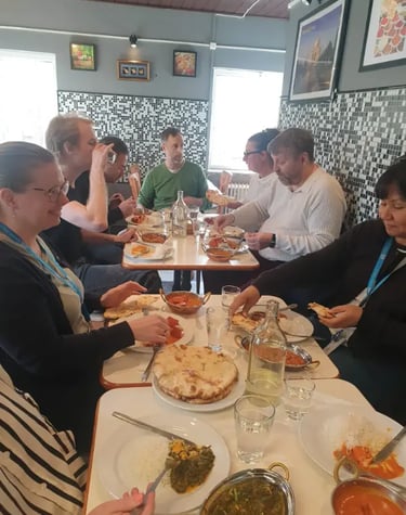 A group of friends sharing authentic Indian cuisine including curry and naan bread at a restaurant.