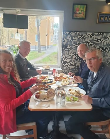 Fyra personer njuter av traditionell indisk mat vid ett restaurangbord med naanbröd och curry.