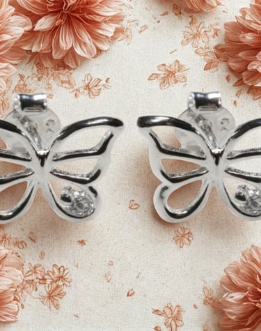 Elegant sterling silver butterfly stud earrings with sparkling cubic zirconia on a floral background.