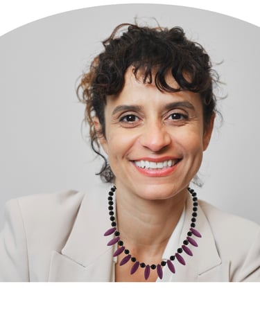 Professional woman with curly hair and purple howlite beaded necklace smiling in a beige blazer.